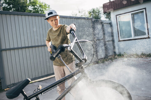 Boy washing bmx bike with pressure washer on yard - VPIF01179