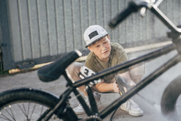 Junge wäscht BMX-Fahrrad mit Hochdruckreiniger auf dem Hof - VPIF01181