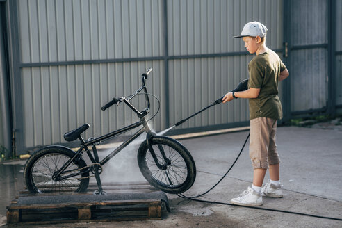 Boy washing bmx bike with pressure washer on yard - VPIF01185