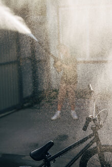 Boy washing bmx bike with pressure washer on yard - VPIF01189