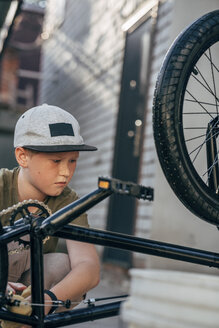 Junge putzt BMX-Fahrrad auf dem Hof - VPIF01191