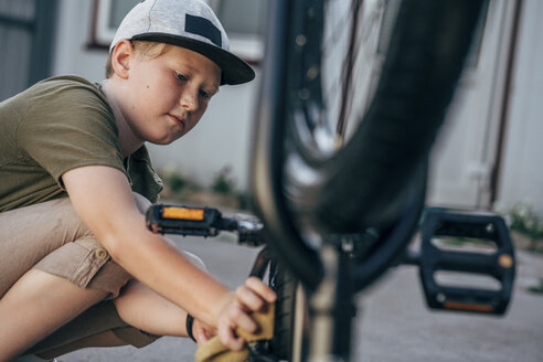 Junge putzt BMX-Fahrrad auf dem Hof - VPIF01192