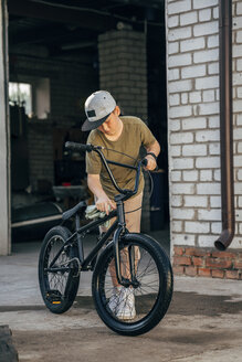 Boy cleaning bmx bike on yard - VPIF01196