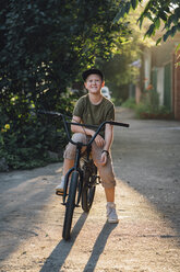 Porträt eines lächelnden Jungen mit BMX-Fahrrad auf der Straße - VPIF01197