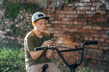 Junge mit BMX-Fahrrad, der ein Mobiltelefon benutzt - VPIF01204