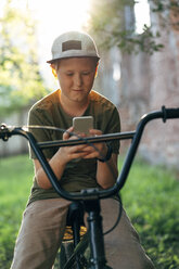 Junge mit BMX-Fahrrad, der ein Mobiltelefon benutzt - VPIF01205