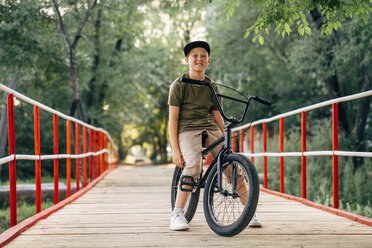 Porträt eines lächelnden Jungen mit BMX-Fahrrad auf einer Brücke - VPIF01207