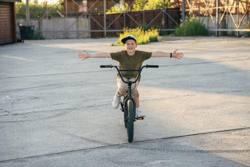 Portrait of smiling boy riding bmx bike freehanded - VPIF01209
