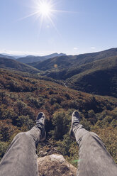 Spanien, Navarra, Irati Forest, Beine eines Mannes baumeln über einer Waldlandschaft im Gegenlicht - RSGF00141