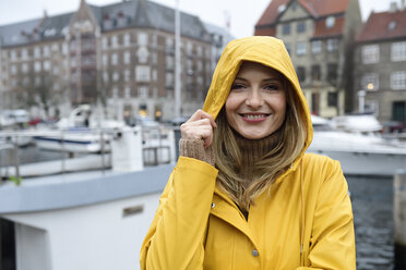 Dänemark, Kopenhagen, Porträt einer glücklichen Frau am Stadthafen bei regnerischem Wetter - ECPF00623