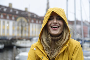 Dänemark, Kopenhagen, Porträt einer glücklichen Frau am Stadthafen bei regnerischem Wetter - ECPF00624