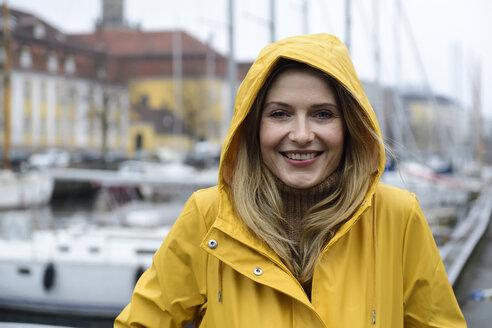 Denmark, Copenhagen, portrait of happy woman at city harbour in rainy weather - ECPF00625