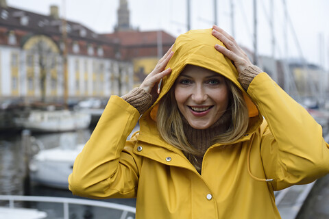 Dänemark, Kopenhagen, Porträt einer glücklichen Frau am Stadthafen bei regnerischem Wetter, lizenzfreies Stockfoto