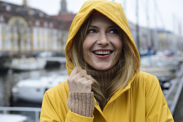 Dänemark, Kopenhagen, Porträt einer glücklichen Frau am Stadthafen bei regnerischem Wetter - ECPF00627