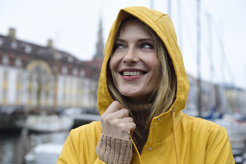 Dänemark, Kopenhagen, Porträt einer glücklichen Frau am Stadthafen bei regnerischem Wetter, lizenzfreies Stockfoto