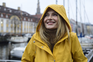 Dänemark, Kopenhagen, Porträt einer glücklichen Frau am Stadthafen bei regnerischem Wetter - ECPF00630