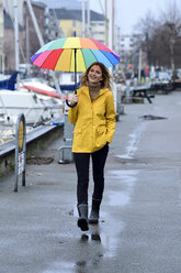 Dänemark, Kopenhagen, glückliche Frau mit buntem Regenschirm beim Spaziergang am Stadthafen - ECPF00633