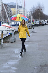 Dänemark, Kopenhagen, glückliche Frau mit buntem Regenschirm beim Spaziergang am Stadthafen - ECPF00634