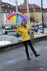 Dänemark, Kopenhagen, glückliche Frau mit buntem Regenschirm am Stadthafen - ECPF00636