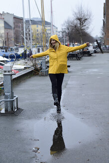 Dänemark, Kopenhagen, glückliche Frau, die am Stadthafen in Pfützen springt - ECPF00639