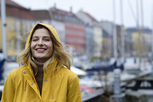 Dänemark, Kopenhagen, Porträt einer glücklichen Frau am Stadthafen bei regnerischem Wetter - ECPF00642