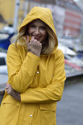 Dänemark, Kopenhagen, Porträt einer glücklichen Frau am Stadthafen bei regnerischem Wetter - ECPF00645
