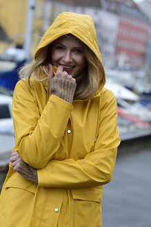 Dänemark, Kopenhagen, Porträt einer glücklichen Frau am Stadthafen bei regnerischem Wetter - ECPF00645