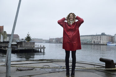 Denmark, Copenhagen, happy woman at the waterfront in rainy weather - ECPF00669