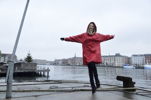 Dänemark, Kopenhagen, glückliche Frau, die bei regnerischem Wetter am Ufer springt - ECPF00670
