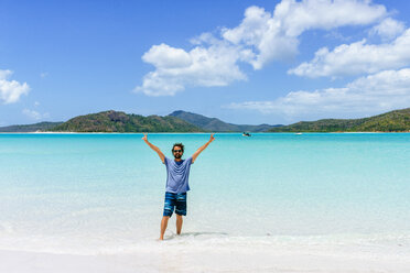 Australien, Queensland, Whitsunday Island, Mann mit erhobenen Armen am Whitehaven Beach stehend - KIJF02485