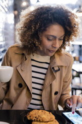Frau benutzt Mobiltelefon in einem Cafe - FMOF00480