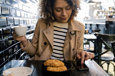 Frau benutzt Mobiltelefon in einem Cafe - FMOF00481