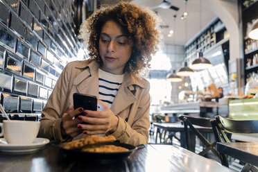 Woman using cell phone in a cafe - FMOF00484
