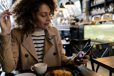 Frau benutzt Mobiltelefon in einem Cafe - FMOF00486