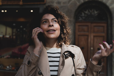 Portrait of woman talking on cell phone looking up - FMOF00492