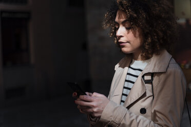 Woman using cell phone in an alley - FMOF00499