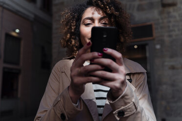 Woman using cell phone in an alley - FMOF00501