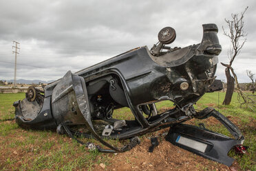 Spanien, Mallorca, Autowrack auf dem Kopf liegend auf einem Feld - JMF00442