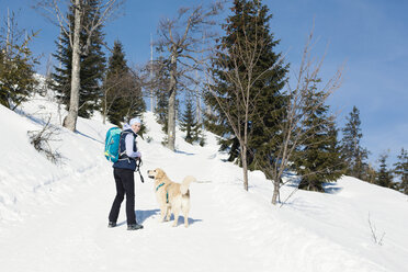 Germany, Bavarian Forest, Lusen, smiling woman with dog hiking in winter - MAEF12830