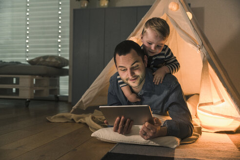 Vater und Sohn teilen sich eine Tafel in einem beleuchteten Zelt zu Hause - UUF16889