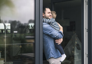 Father hugging son at terrace door at home - UUF16896