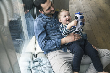 Father and son playing with a toy robot at home - UUF16897