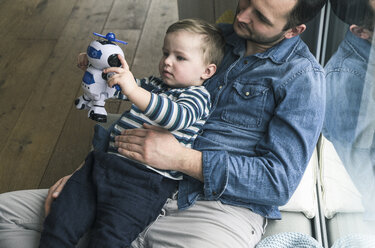 Father and son playing with a toy robot at home - UUF16899