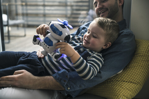 Vater und Sohn spielen mit einem Spielzeugroboter zu Hause, lizenzfreies Stockfoto