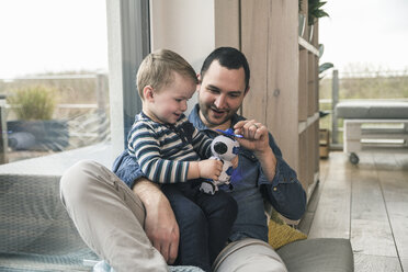 Father and son playing with a toy robot at home - UUF16903