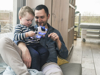 Father and son playing with a toy robot at home - UUF16904