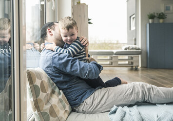 Vater kuschelt zu Hause mit seinem Sohn - UUF16913