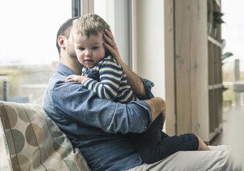 Vater kuschelt zu Hause mit seinem Sohn - UUF16914