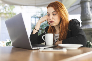 Portrait of redheaded young woman at pavement cafe looking at laptop - WPEF01443