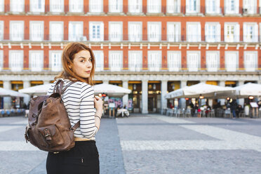 Spain, Madrid, Plaza Mayor, portrait of redheaded young woman with backpack in the city - WPEF01450